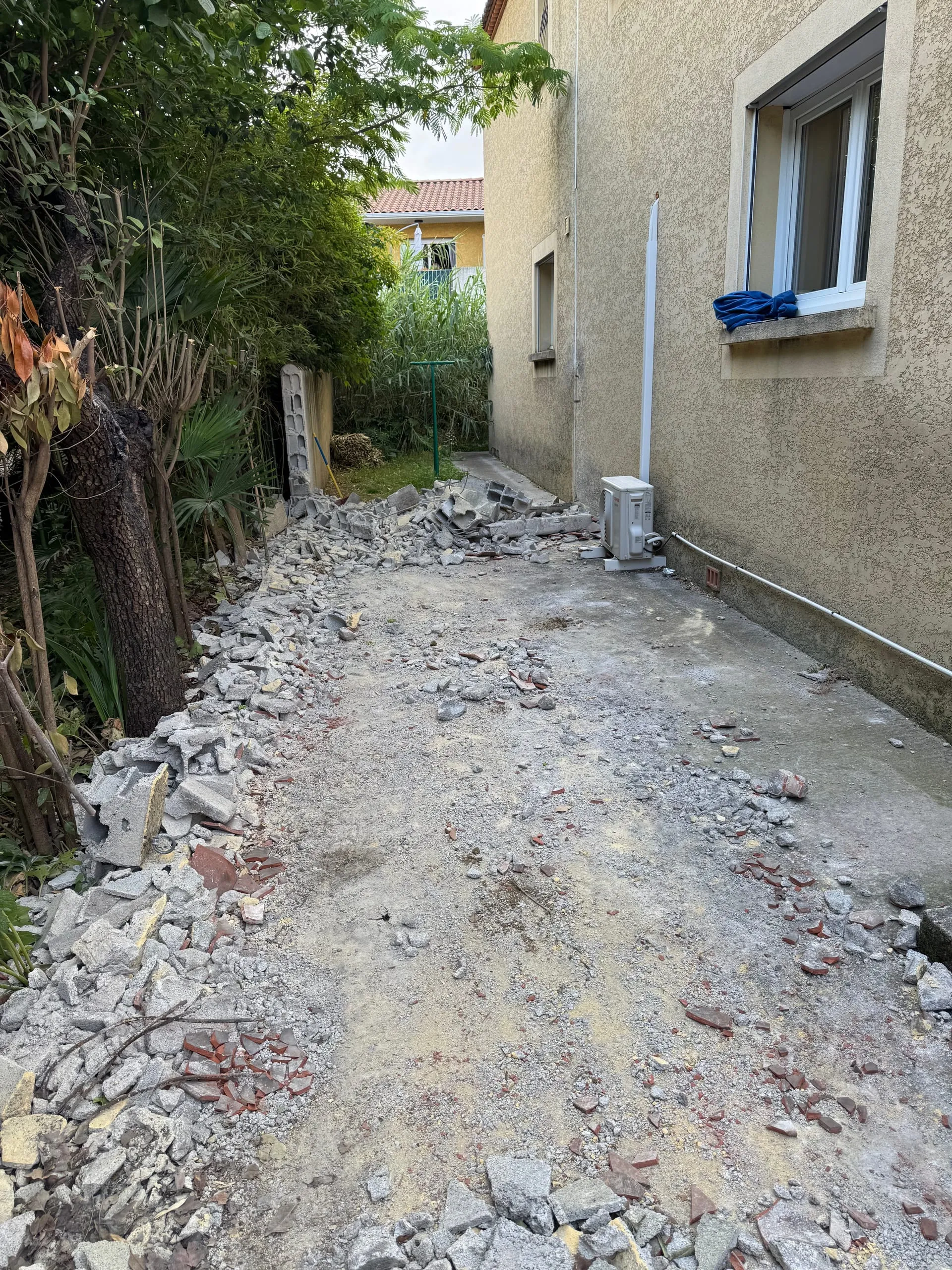 Dalle et muret démolis laissant apparaître des gravats et des morceaux de béton