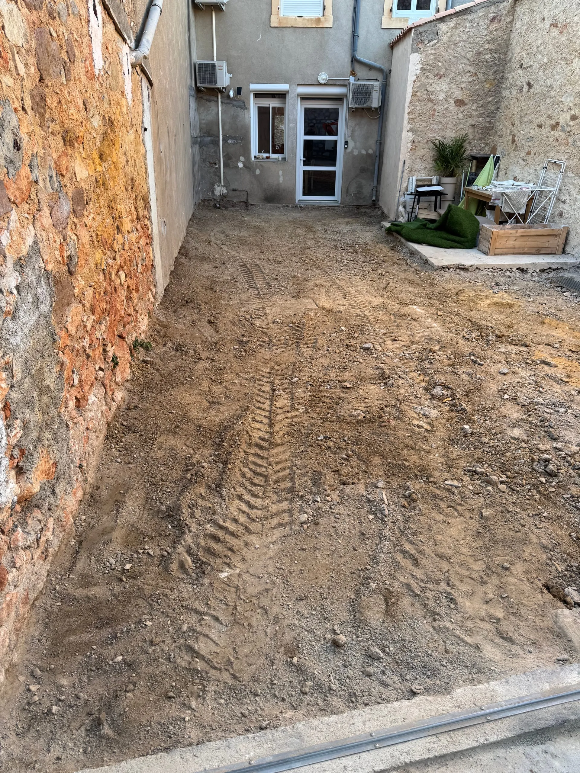 Décaissement d’une cour intérieure entre des murs en pierre.