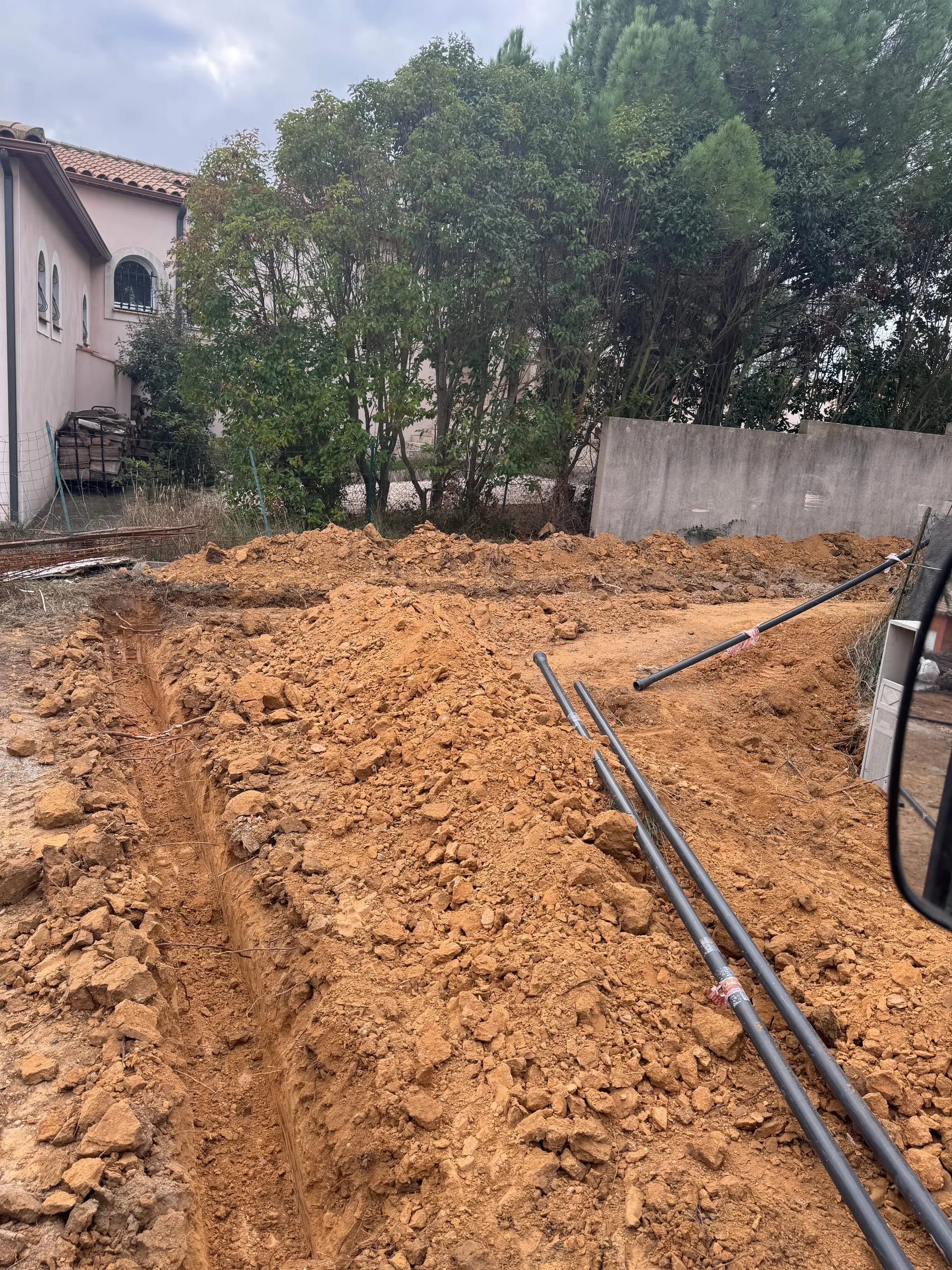 Tranchées de terrassement avec gaines noires posées sur un terrain résidentiel