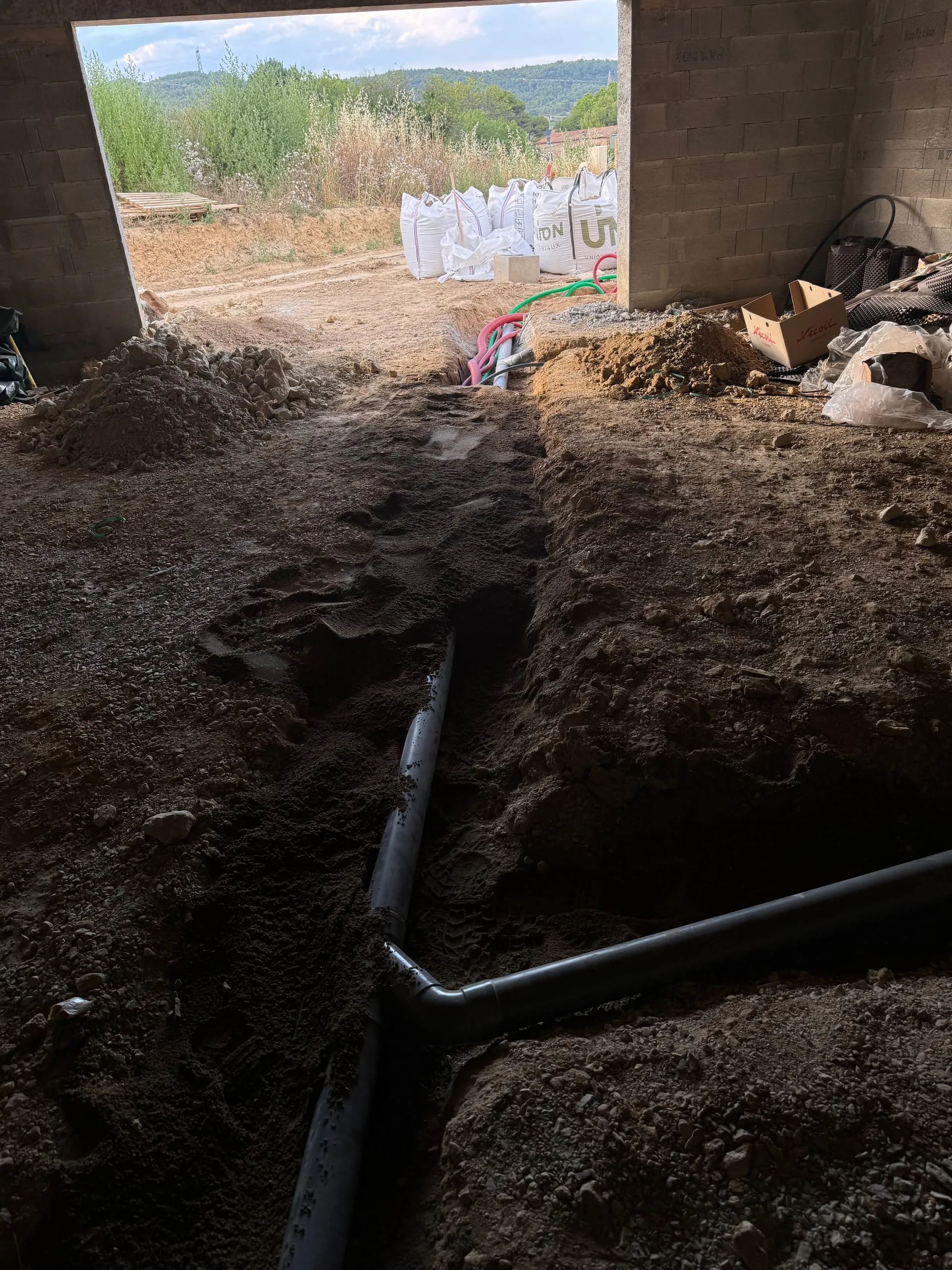 Passage de gaines et de conduites dans une tranchée à l’intérieur d’une construction en cours.