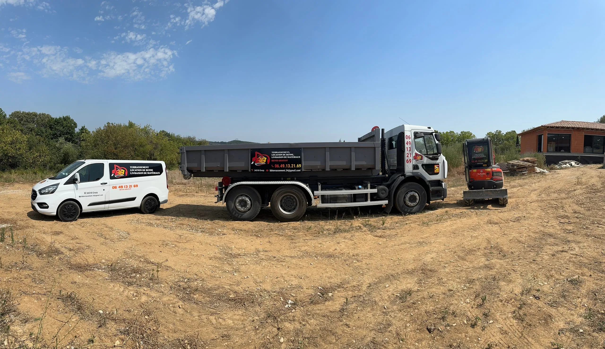 Camionnette, camion porte-benne et mini-pelle de BB Terrassement alignés sur un terrain de chantier