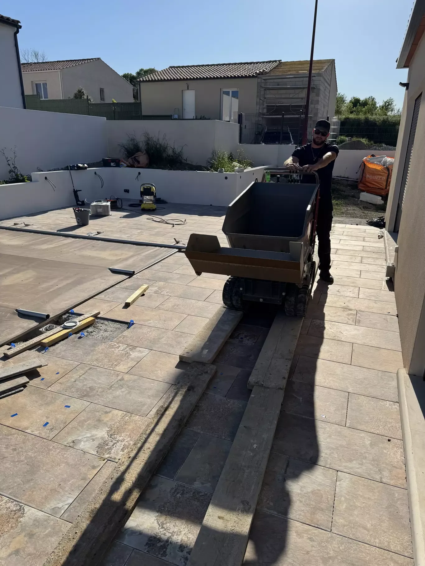 Ouvrier manœuvrant un mini-dumper sur une terrasse en cours d’aménagement extérieur