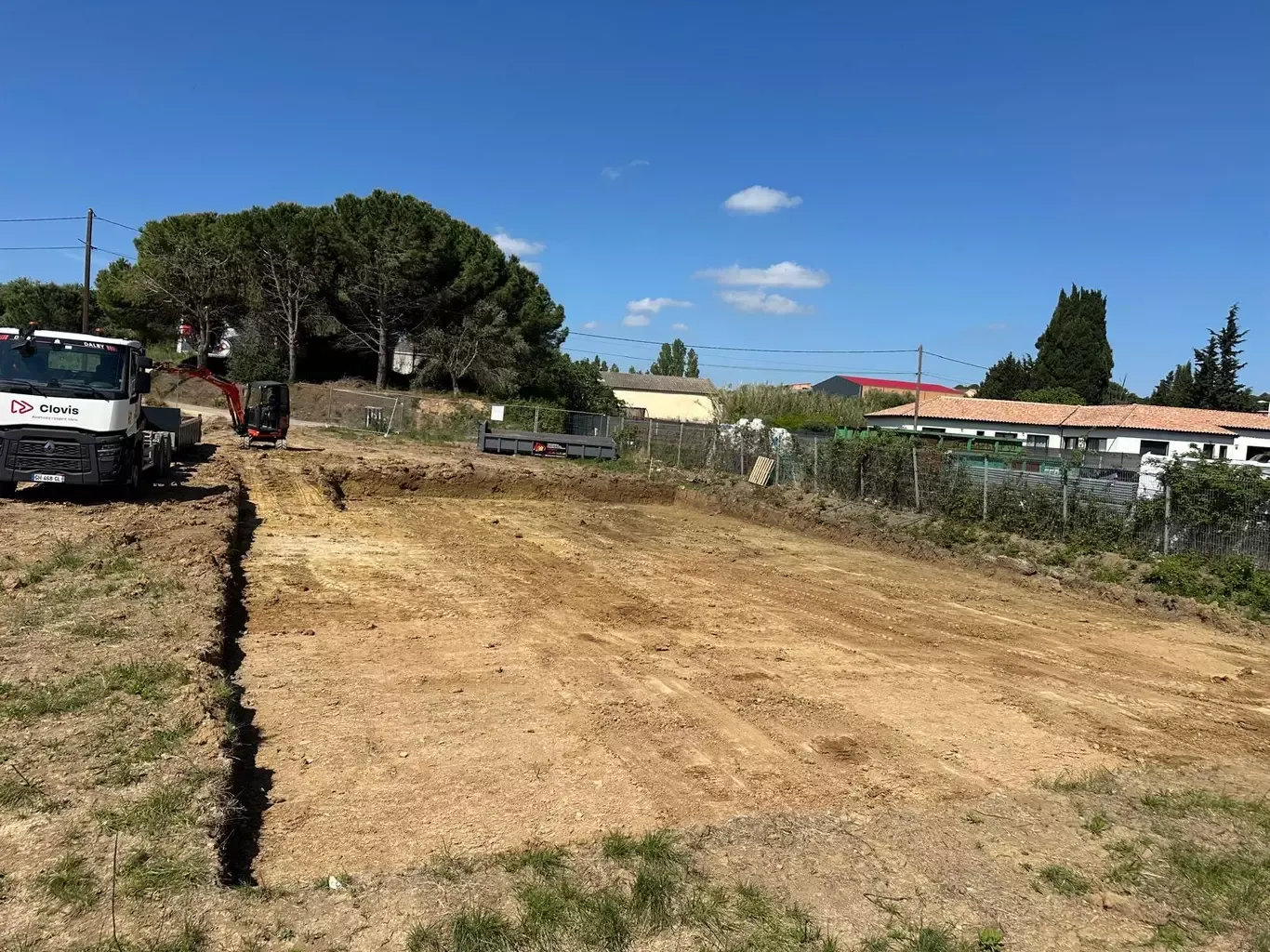 Terrain décaissé et nivelé lors de travaux de terrassement, avec camion et mini-pelle