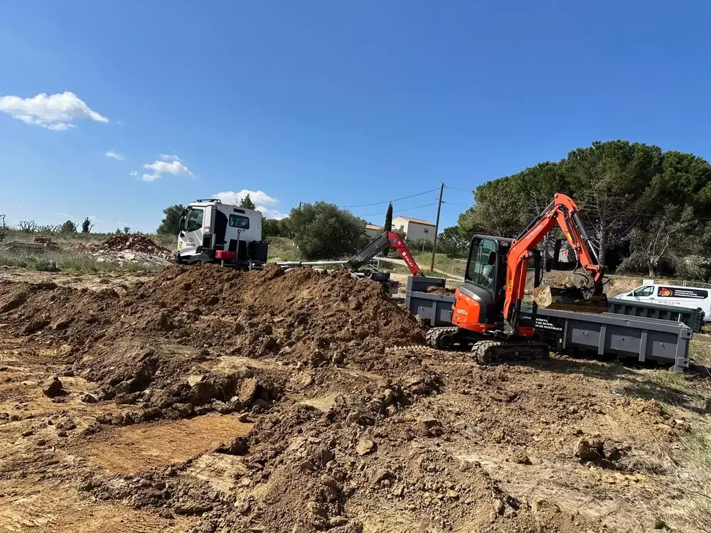 Mini-pelle orange chargeant de la terre dans une benne sur un chantier de terrassement