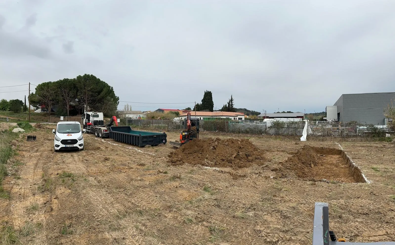Travaux de terrassement et excavation d'un terrain avec une pelle mécanique et un camion-benne.