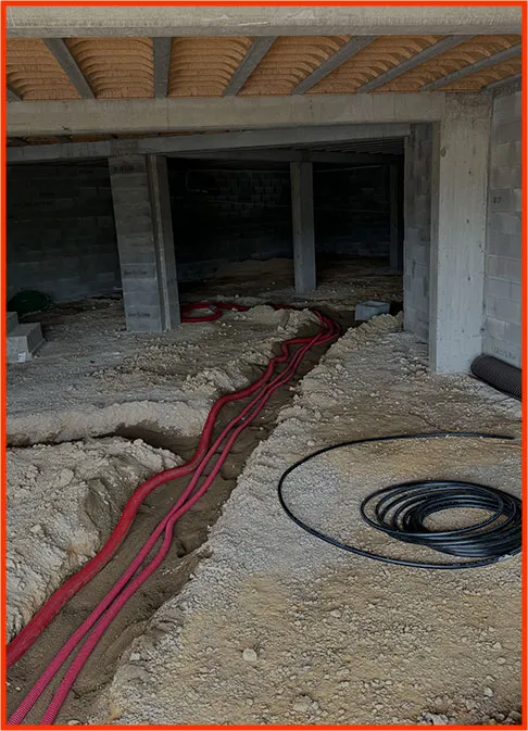 Gaines rouges posées dans une tranchée au pied d’une construction en parpaings