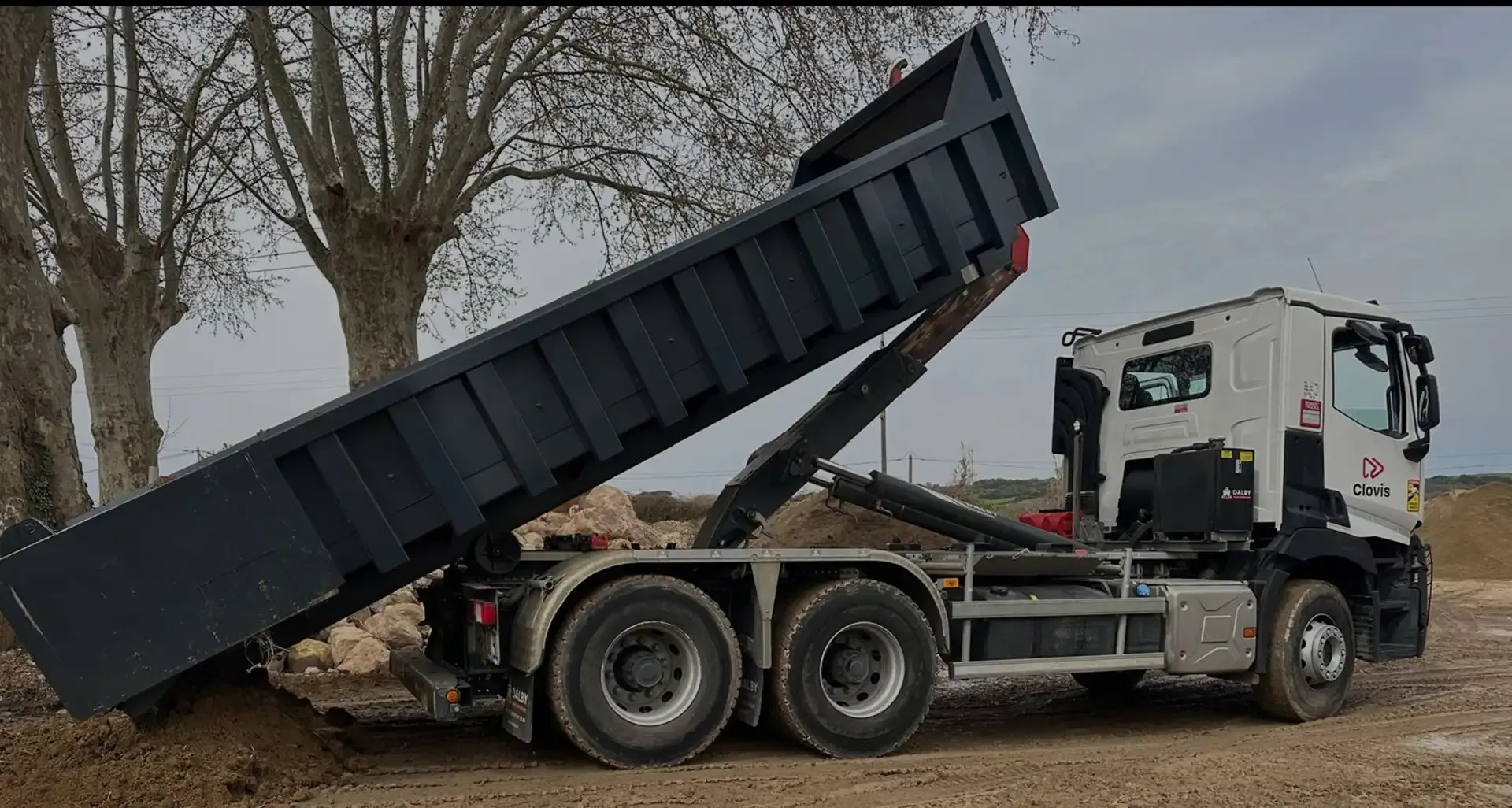 Camion à benne basculante déchargeant des matériaux sur un terrain