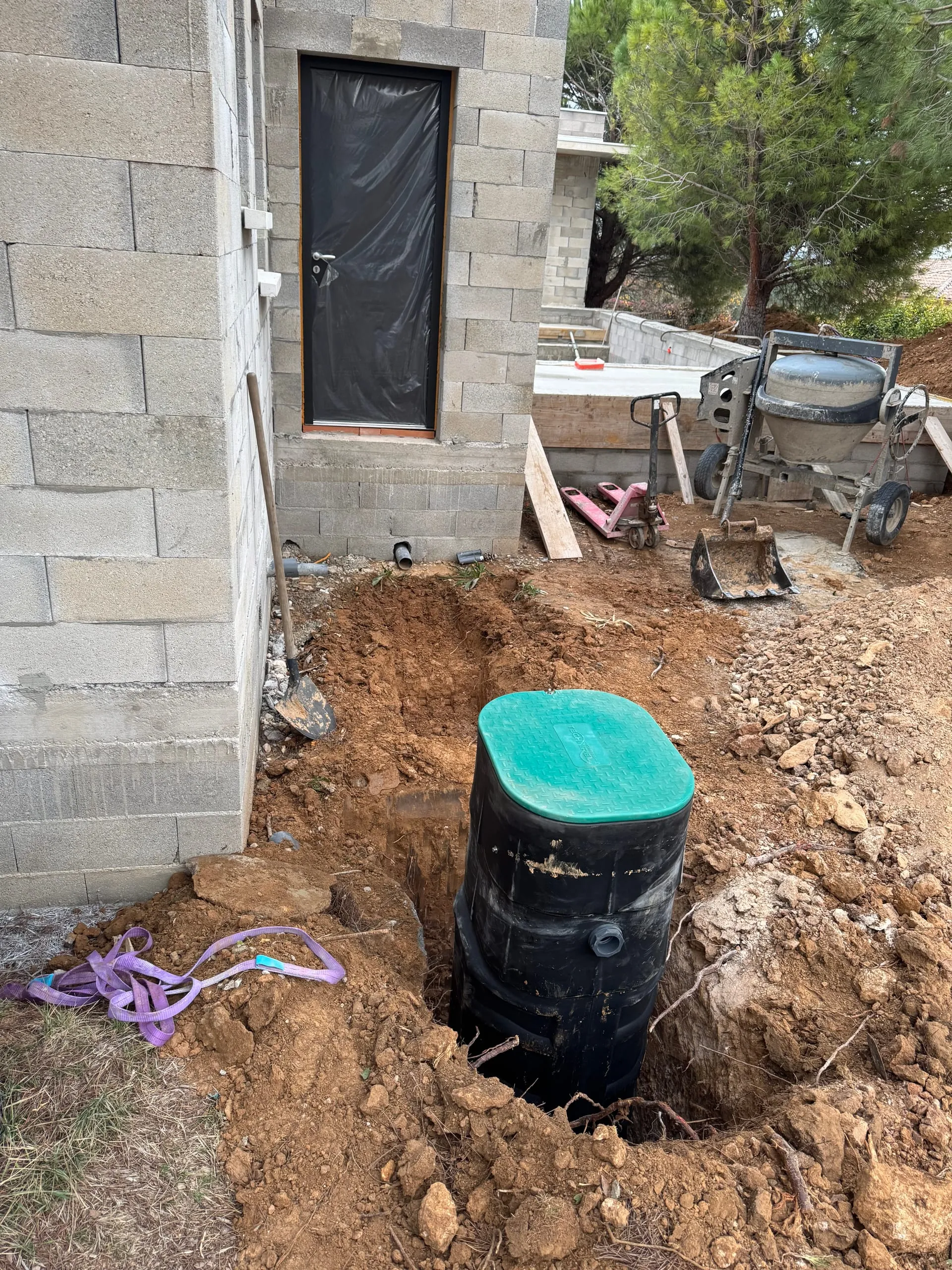 Poste de relevage noir installé dans une excavation devant une maison